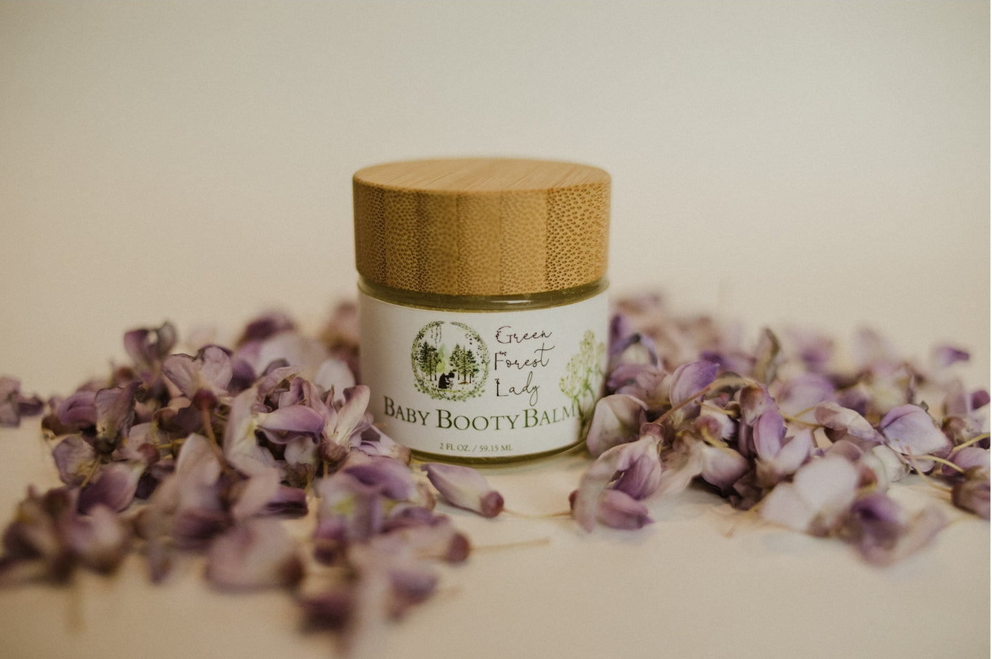 Jar of Baby Booty Balm surrounded by flower pedals