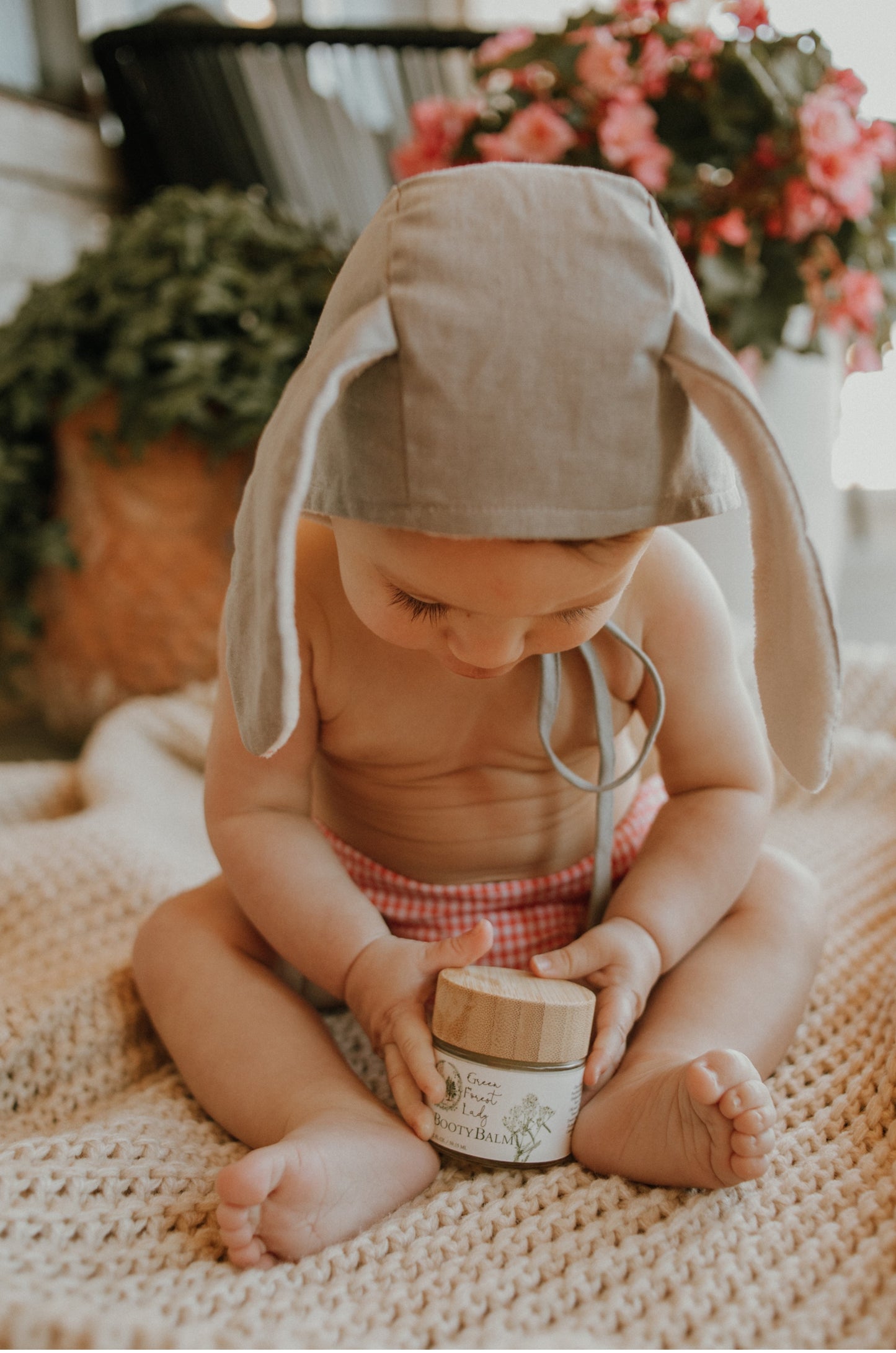 Baby holding a jar of Baby Booty Balm